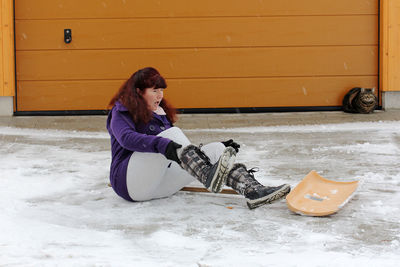 Full length of woman sitting on snow covered field