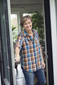 Portrait of mature woman opening door of house