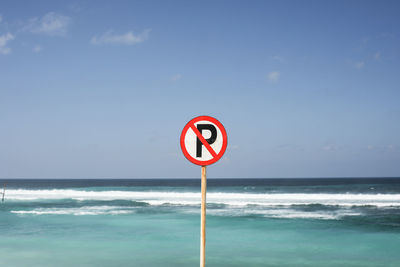 Information sign on beach against sky