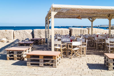 Chairs and tables on beach against clear sky