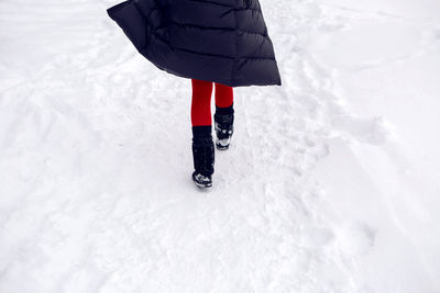 Girl running in a snowy field in a jacket and sunglasses