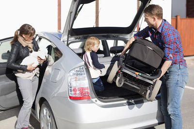 Parents with children entering into car on street