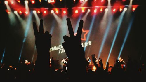 Cropped hands showing peace sign at music concert