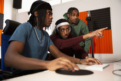 Rapper pointing while sitting with sound engineer in recording studio