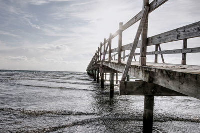 Bridge over calm sea against sky