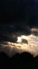 Low angle view of silhouette trees against dramatic sky