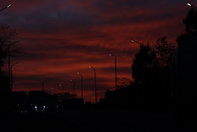 Silhouette street against orange sky at sunset