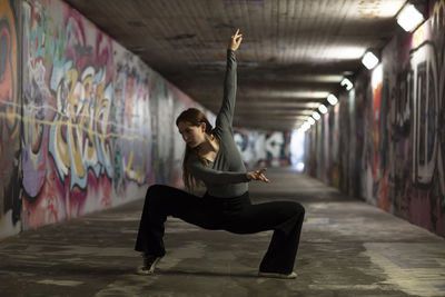 Full length of woman dancing in illuminated tunnel