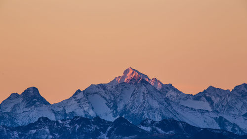 Scenic view of snowcapped mountains against orange sky