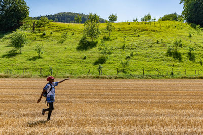 African woman dancing on golden harvested corn field in hot sun in linn bözberg, switzerland.