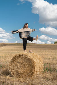 Girl on a rye field with haystack wearing striped sweater