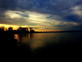 Scenic view of lake against cloudy sky during sunset