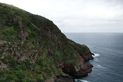 Scenic view of sea by cliff against sky