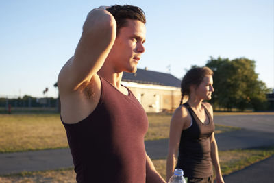 Side view of young couple standing against sky