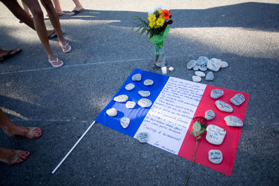 Low section of people standing by french flag and bouquets on road