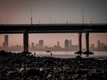 Silhouette of people on bridge against sky during sunset