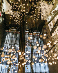 Low angle view of illuminated pendant lights hanging on ceiling in building