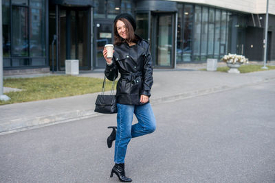 Woman going to work with coffee walking near office building