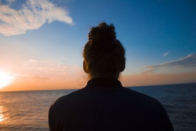 Rear view of man looking at sea against sky