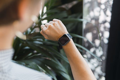 Young woman checking time on smart watch at coffee shop