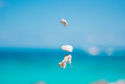 Full length of man hanging on rope against blue sky
