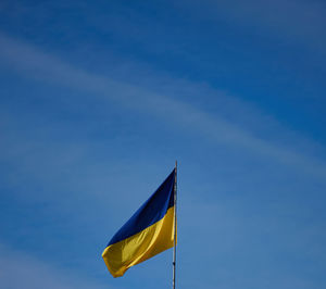 The yellow-blue flag of ukraine is flying on a building in kherson against the blue sky