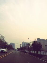 Cars on road in city against clear sky