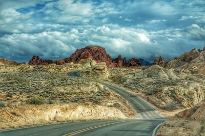 Road leading towards mountains against sky