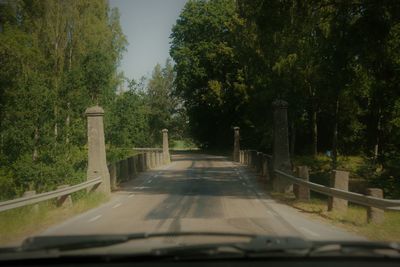 Road amidst trees seen through car windshield