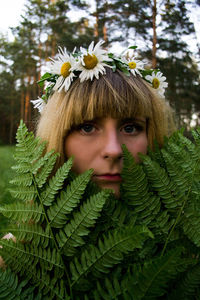 Portrait of young woman with flowers amidst plants