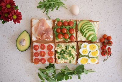 Healthy toast for breakfast with avocado, eggs, tomatoes, arugula etc