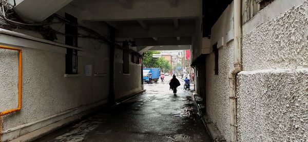 People walking on narrow street amidst buildings in city