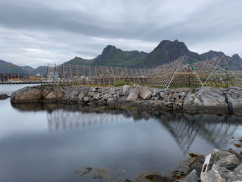 Svolvær and empty fishing industry equipment by sea against mountain and sky