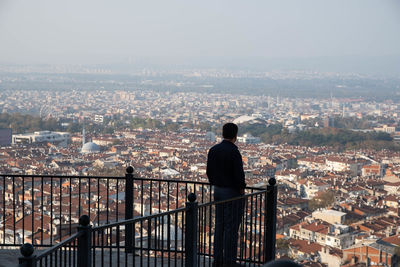 Rear view of man looking at cityscape against sky