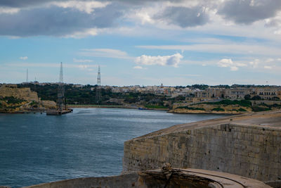 View of sea and buildings against cloudy sky