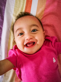 Portrait of cute baby girl on bed at home