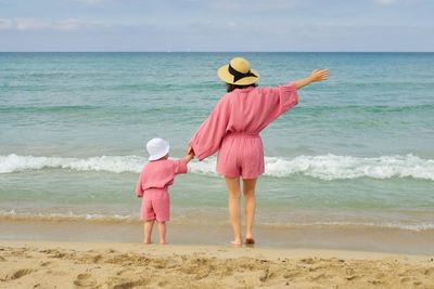 Rear view of woman standing at beach