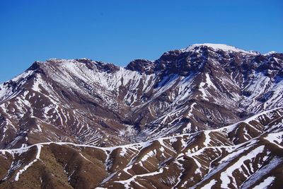 Low angle view of snowcapped mountain against clear blue sky