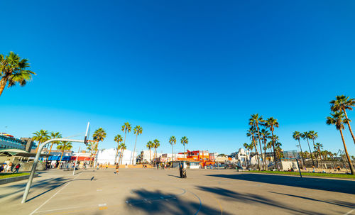 People walking on road against blue sky