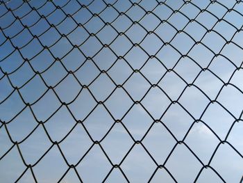 Low angle view of chainlink fence against clear blue sky