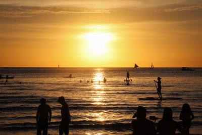 Silhouette people on beach against sky during sunset