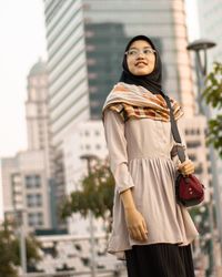Low angle view of smiling woman standing in city