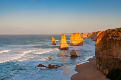 Rock formation on sea against clear sky