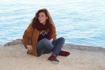 Portrait of smiling young woman sitting on shore