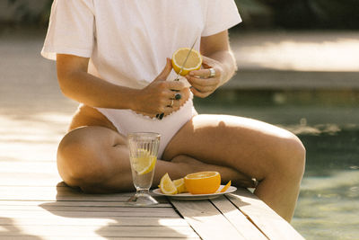 Midsection of woman cutting fruit sitting at a pool 