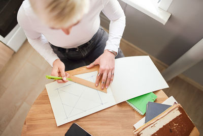 High angle view of boy holding paper with text on table