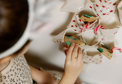 The girl takes out a gift from the pocket of the wall advent calendar.