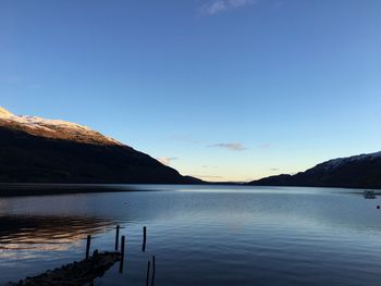 Scenic view of lake by mountains against blue sky