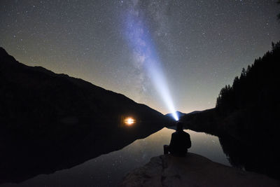 Silhouette woman standing on mountain against sky at night