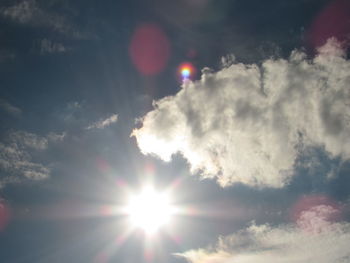 Low angle view of sunlight streaming through clouds